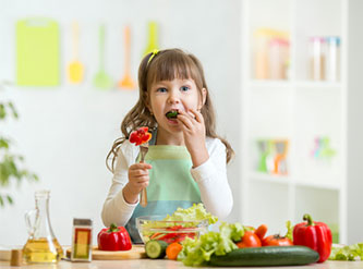 Little girl eats fruit.